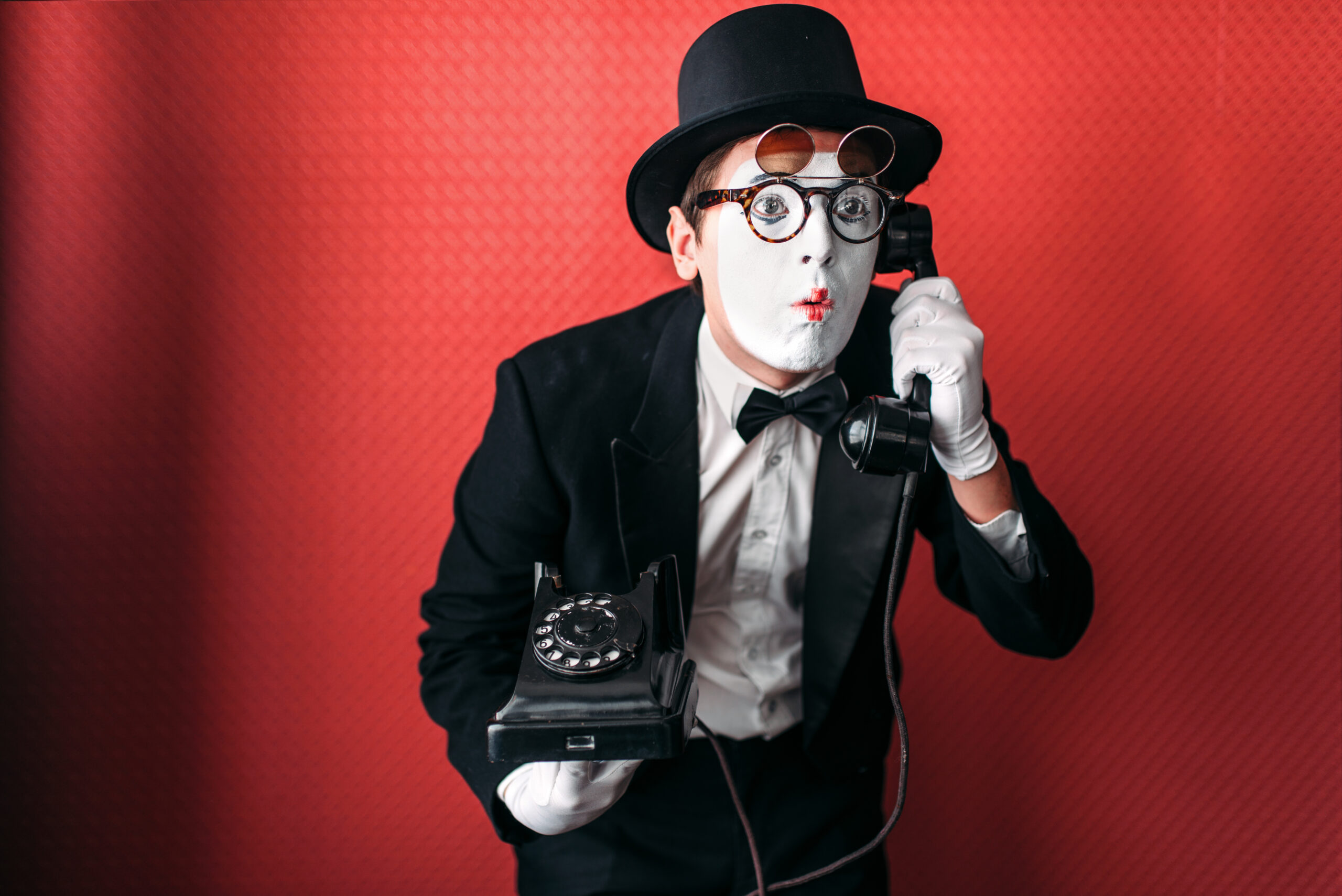 Mime theater actor performing with old telephone Mime theater actor performing with old telephone. Comedy pantomime artist in suit, gloves and hat