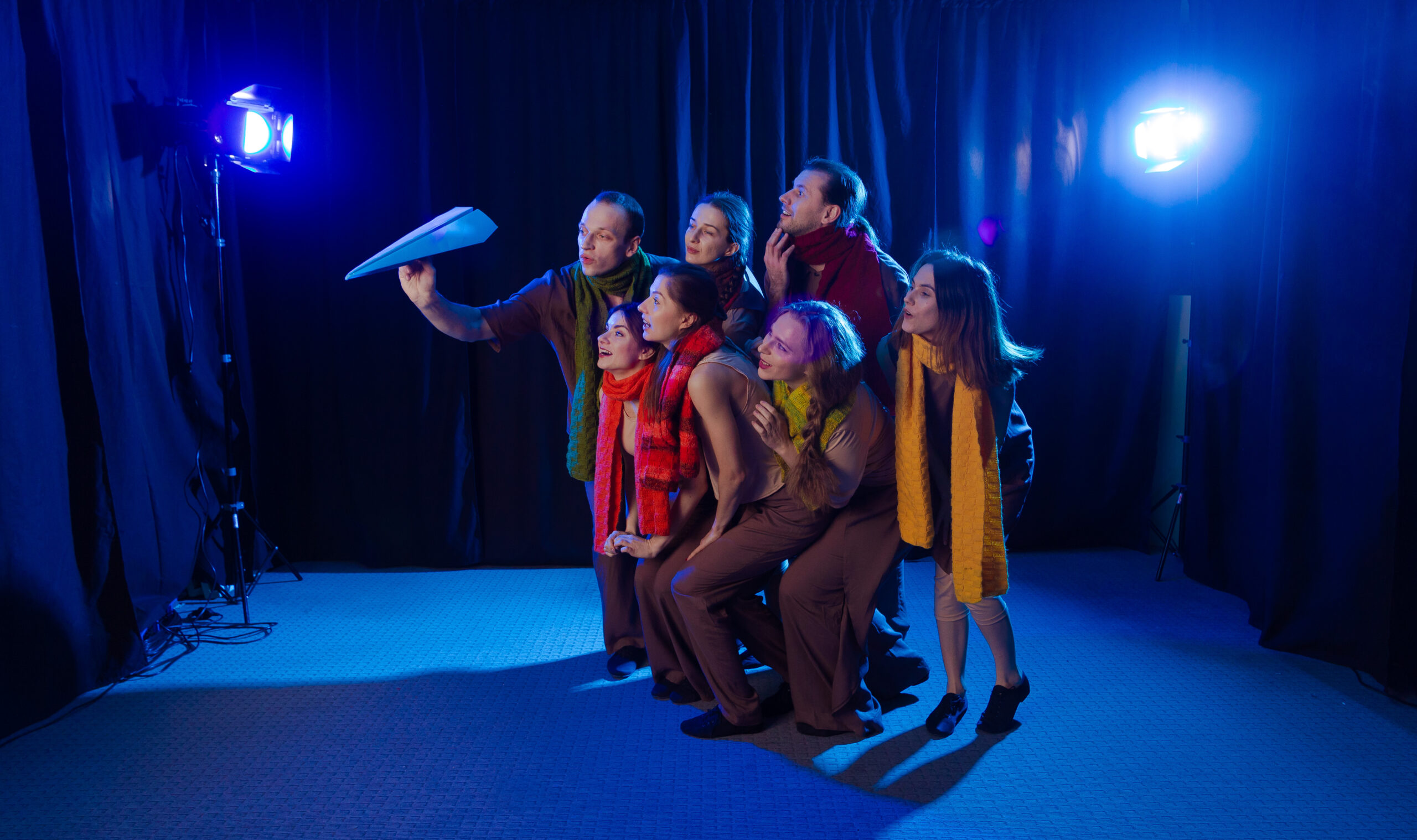 The actors on the stage play a performance and look at a blue paper plane. The actors on the stage play a performance and look at a blue paper plane.